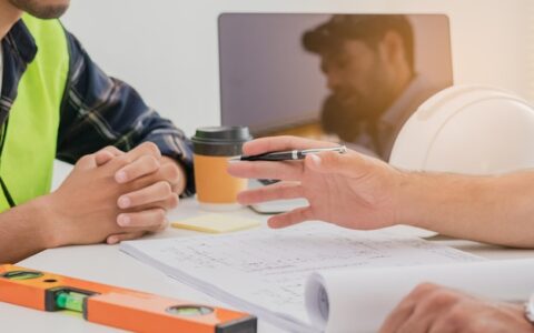 Grupo, equipe de asiáticos, caucasianos jovens colegas ou empreiteiros, brainstorming de engenheiro, discutindo e conversando para planejar a planta, papelada, em cima da mesa no local de trabalho, escritório. Conceito de pessoas trabalhadoras.