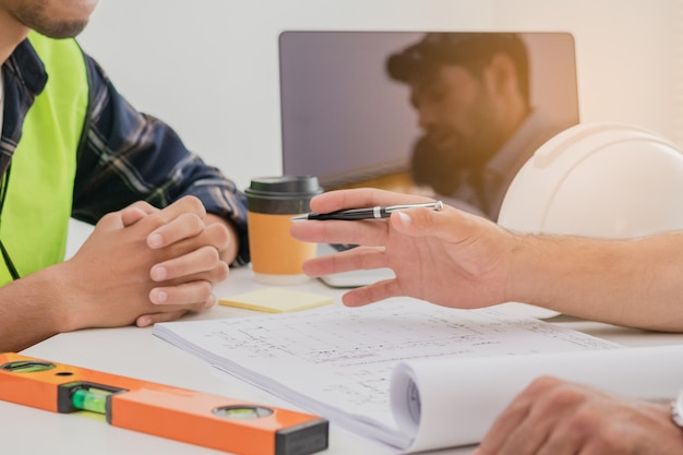 Grupo, equipe de asiáticos, caucasianos jovens colegas ou empreiteiros, brainstorming de engenheiro, discutindo e conversando para planejar a planta, papelada, em cima da mesa no local de trabalho, escritório. Conceito de pessoas trabalhadoras.