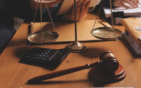Jovem advogada atraente no escritório Mulher de negócios e advogados discutindo papéis de contrato com balança de latão em uma mesa de madeira no escritório Serviços jurídicos de direito Conselhos de justiça e conceito imobiliário